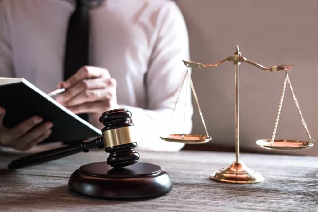 A wooden gavel and legal scales representing the regulations and safety standards for nicotine salt products.