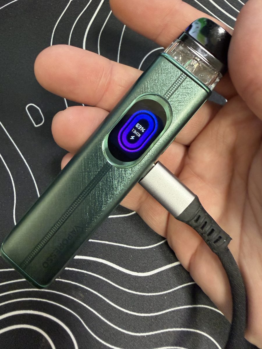 Vaporesso XROS 6 held in hand while fast charging, screen lit